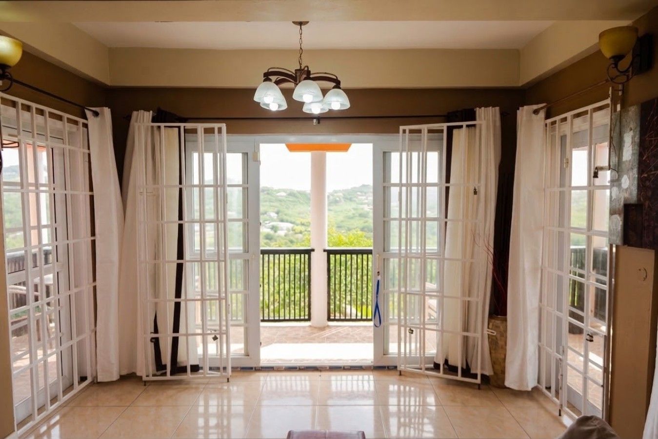 Ein Zimmer mit einer großen Glasdoor, die auf einen Balkon mit Blick auf Grünflächen führt.