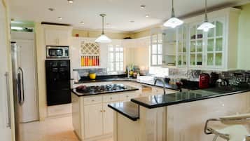 A spacious kitchen with a central island, white cabinetry, and a stainless steel range hood.