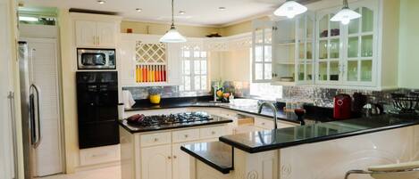 A spacious kitchen with a central island, white cabinetry, and a stainless steel range hood.