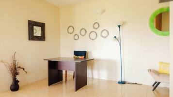 A room with a desk, chair, lamp, wall decorations, and a vase.