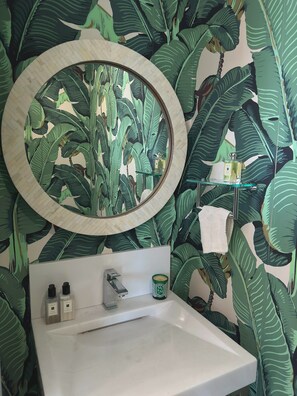 Une salle de bain avec un lavabo, un miroir et un espace douche.