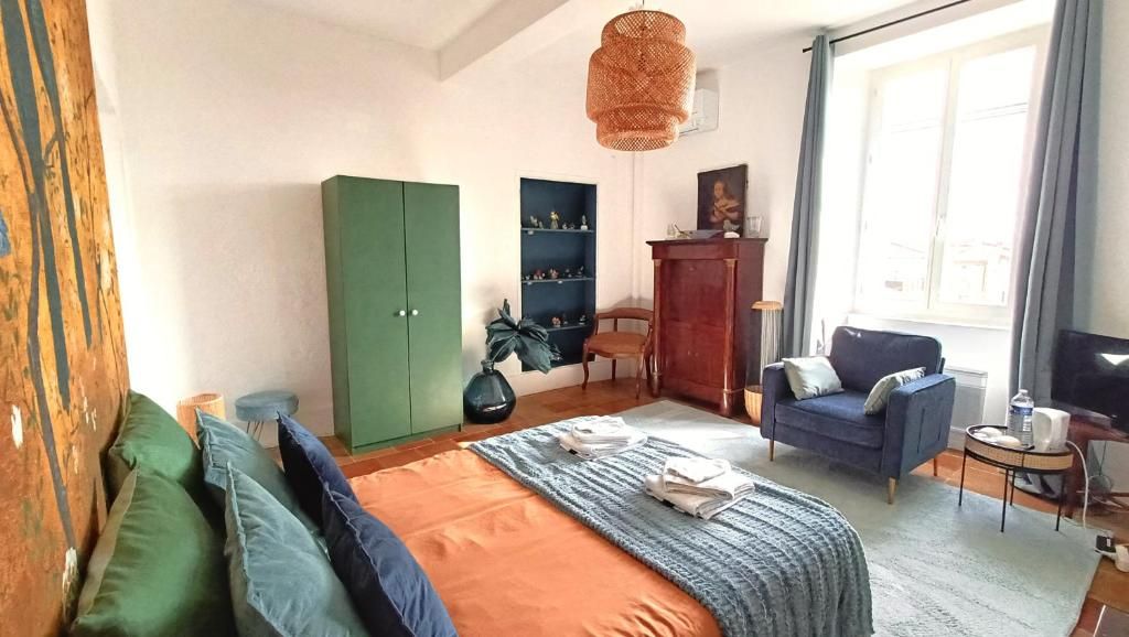 Un dormitorio con una cama, un armario verde, un sofá azul y un televisor.