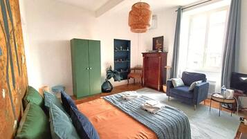 Un dormitorio con una cama, un armario verde, un sofá azul y un televisor.
