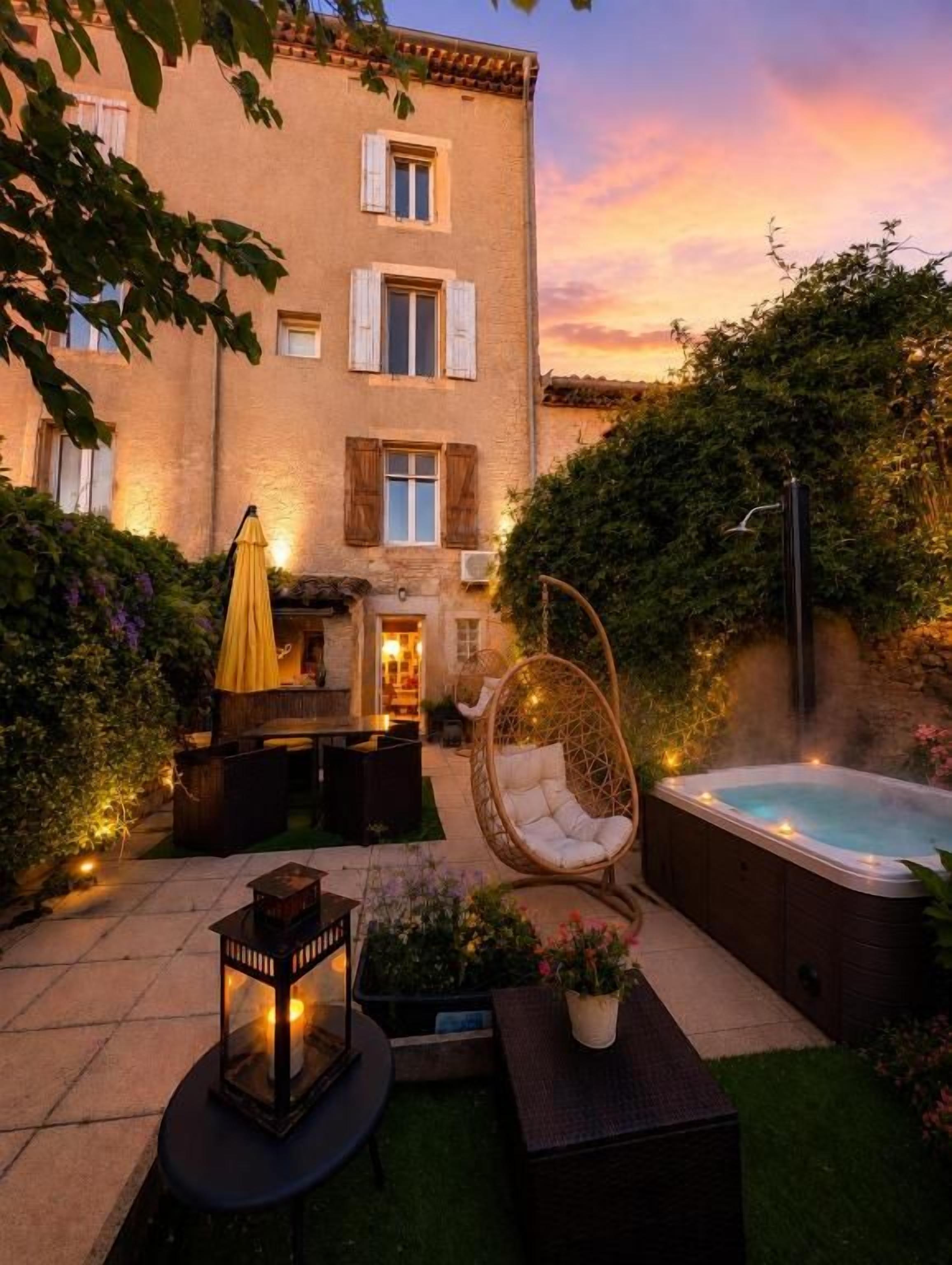 Un patio con un jacuzzi, mobiliario exterior y un edificio con ventanas.