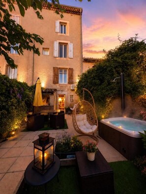 A courtyard with a hot tub, outdoor furniture, and a building with windows.