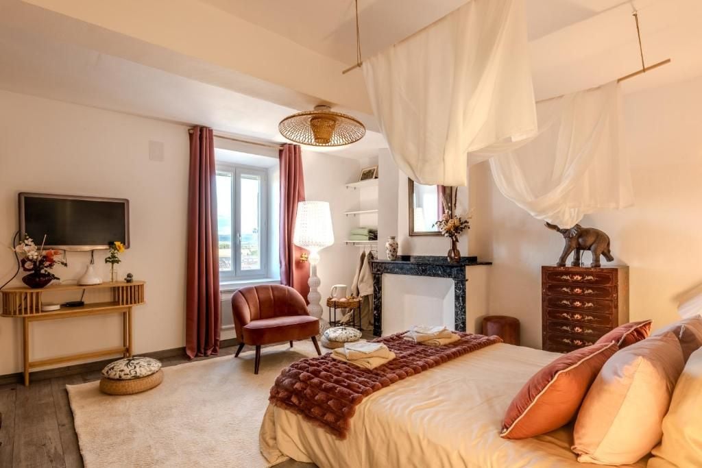 Habitació d'hotel amb llit, televisió, cadira, escriptori i una llar de foc.