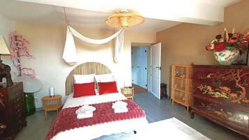 Une chambre à coucher comprenant un lit, une table de chevet, une lampe, une commode et une porte donnant sur une autre pièce.
