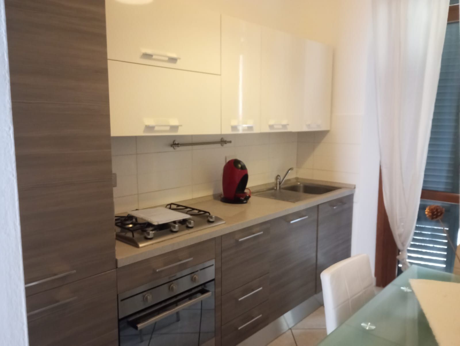 Una cocina moderna con estufa a gas, un lavamanos y una zona de comedor con mesa.