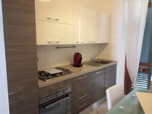 Eine moderne Küche mit Gasherd, Spüle und einem Essbereich mit Tisch.