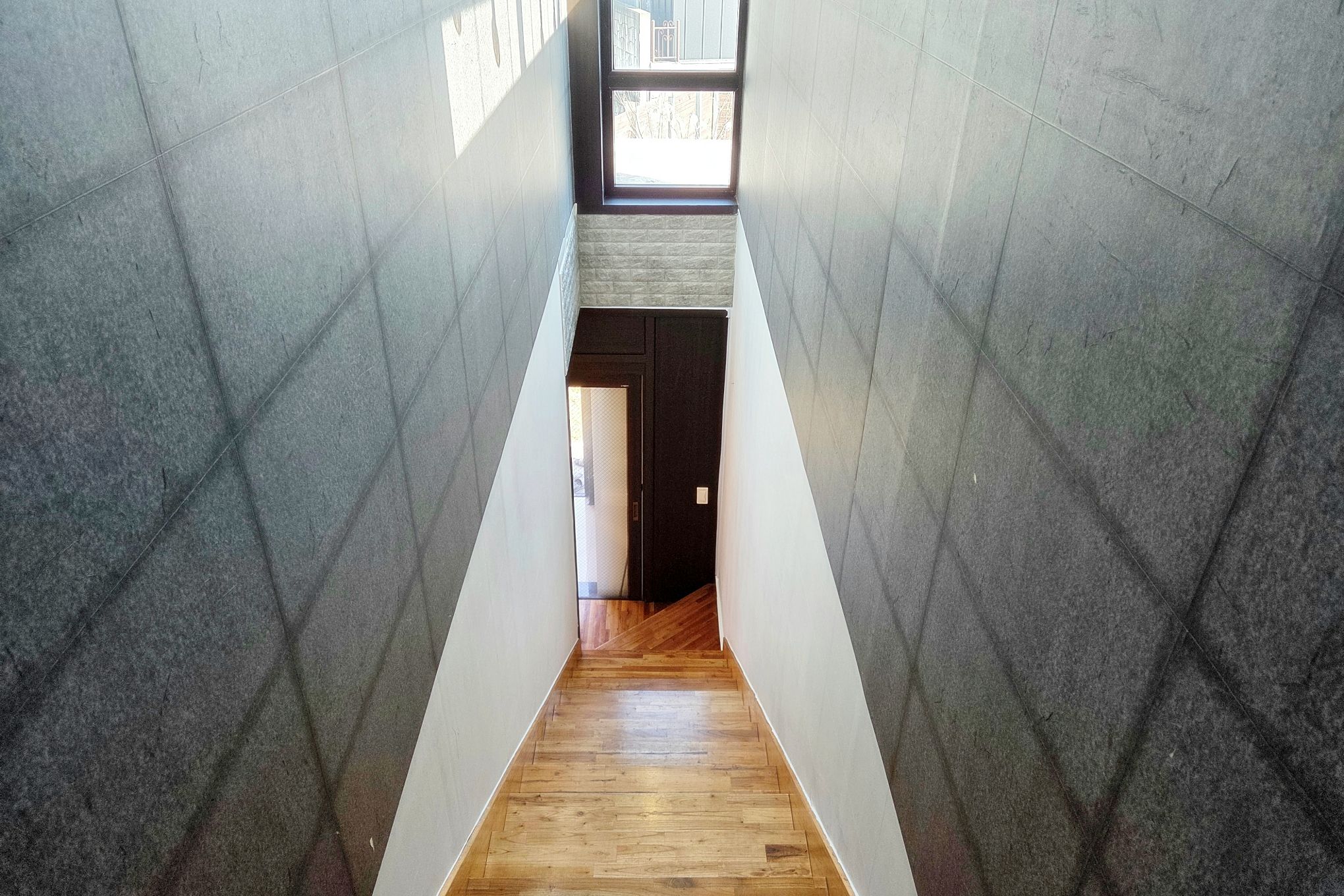 A narrow hallway with a wooden floor leading to a door at the end.