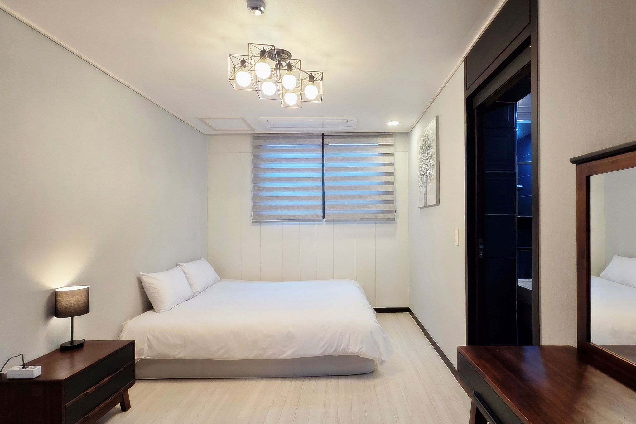 A bedroom with a bed, bedside table, lamp, and a ceiling light fixture.