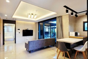 A modern living room with a sofa, dining table, and chairs. - dalkompoolvilla (Jeju-si)