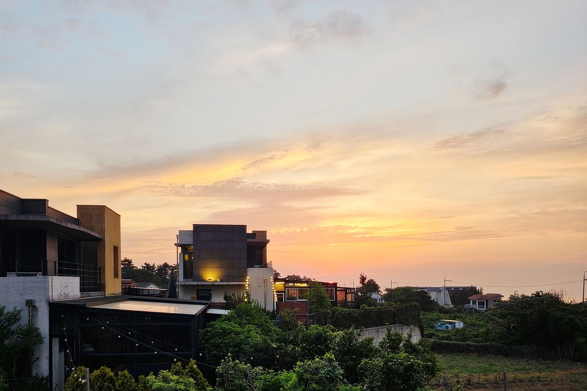 A modern building with a flat roof and a flat facade, surrounded by greenery.