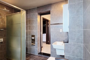 Un baño moderno con cabina de ducha de vidrio, lavamanos integrado y ducha a pie.