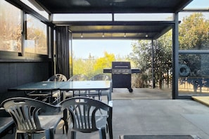 An outdoor patio with a glass enclosure, a grill, and seating. - dalkompoolvilla (Jeju-si)