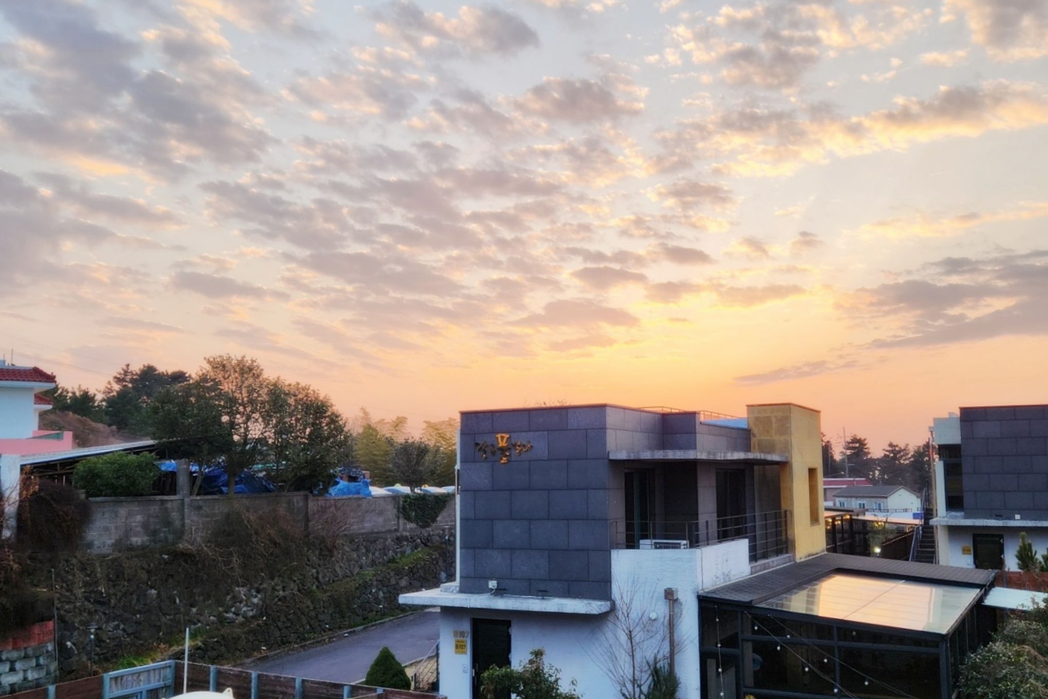 A modern building with a flat roof and a flat facade, surrounded by trees and other buildings.