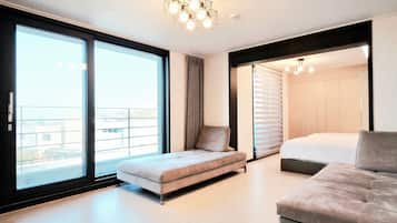 A modern bedroom with a sofa, a bed, and a large window.
