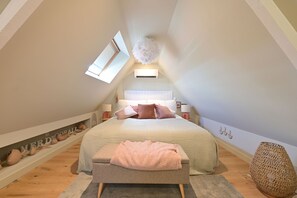 A bedroom with a sloped ceiling, a skylight, a bed with multiple pillows, a bedside table, and a decorative wall shelf. - Extraordinaire Villa 5 étoiles 12 personnes 7 min Lille (Marcq-en-Barœul)