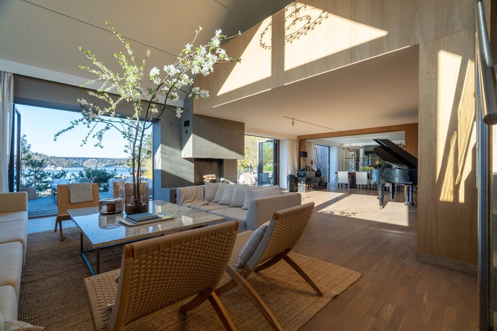 A spacious living area with a large window, a piano, and a view of a bridge.