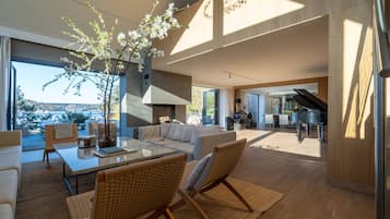 A spacious living area with a large window, a piano, and a view of a bridge.