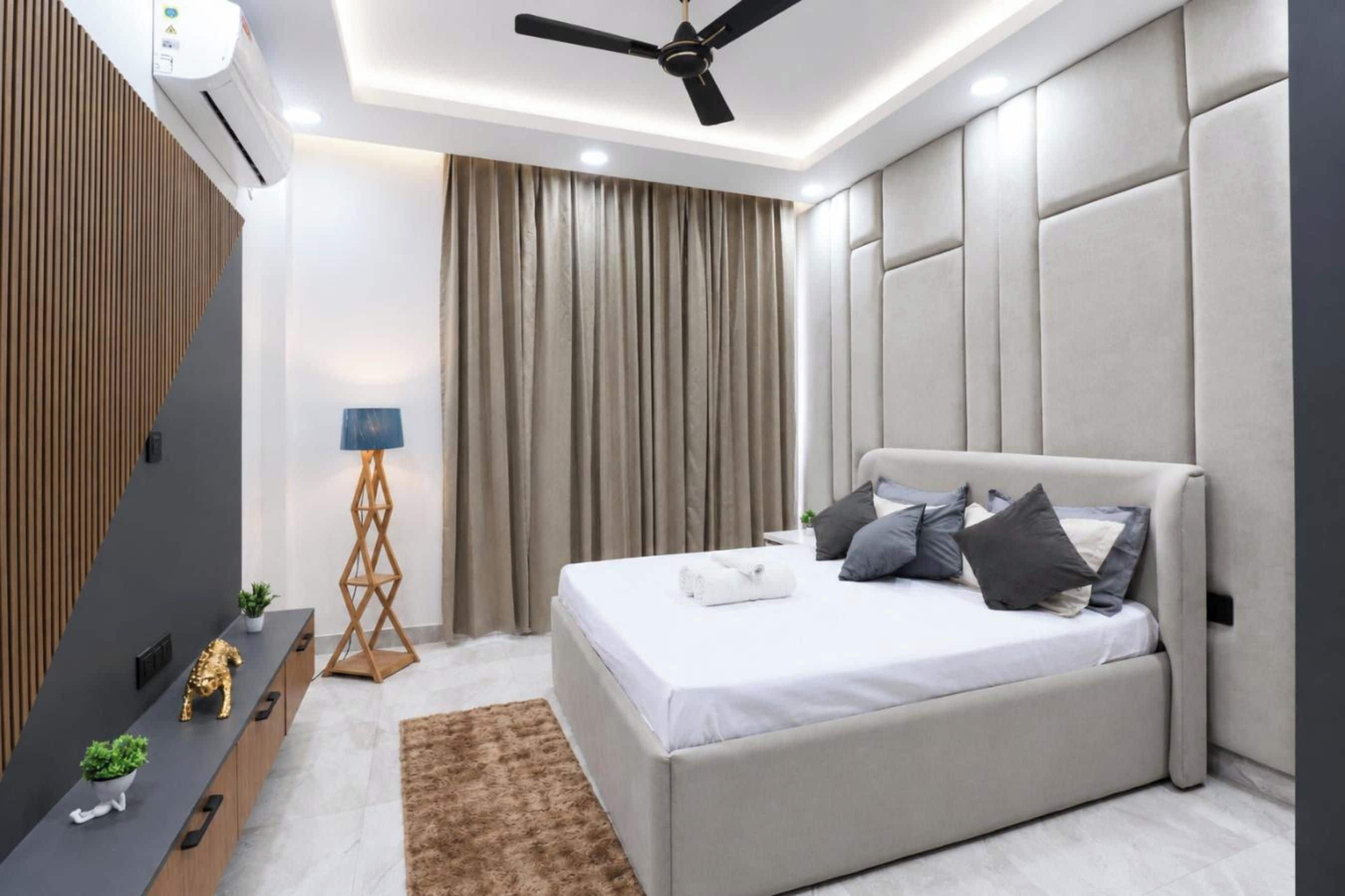 A modern bedroom with a bed, a ceiling fan, a desk, and a floor lamp.