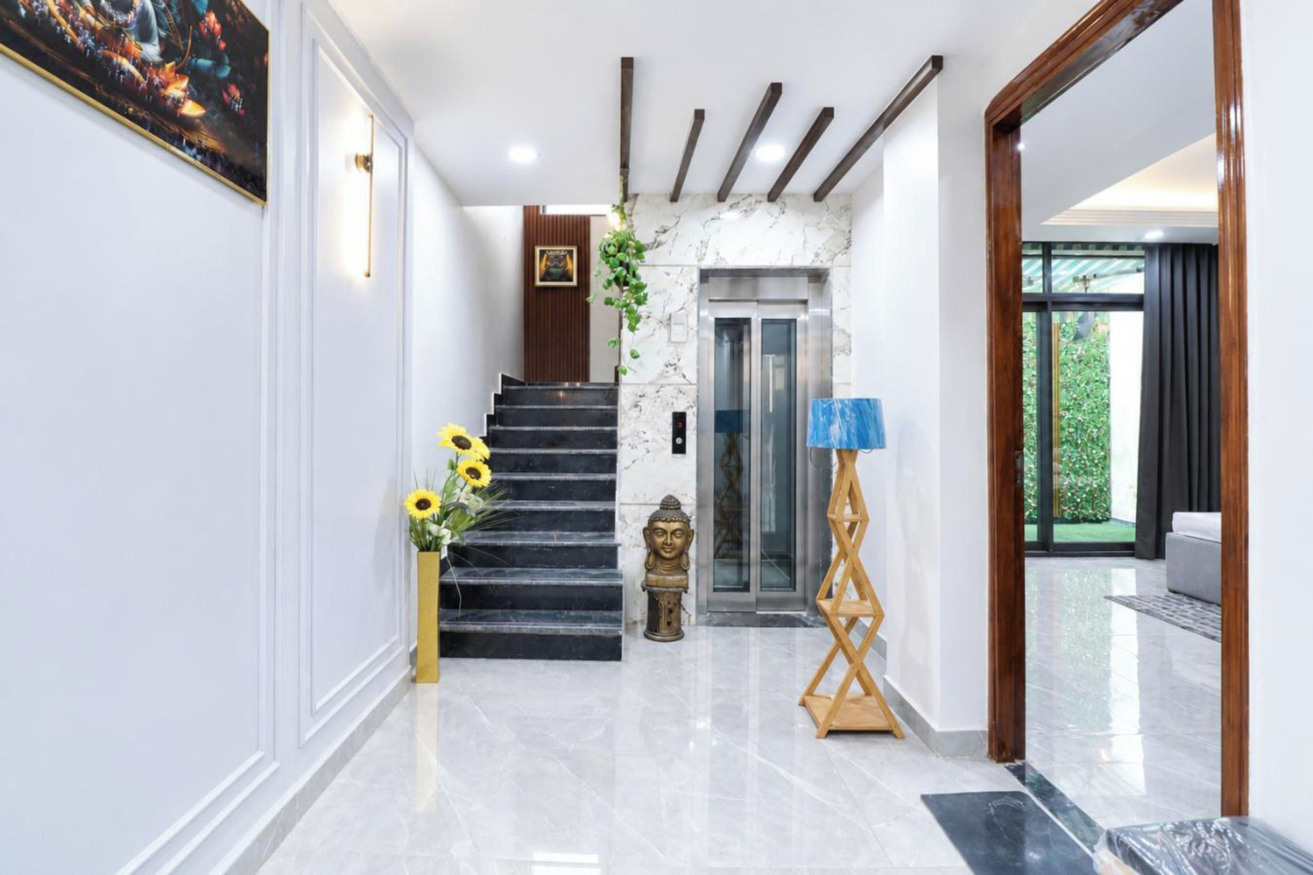 Ein modernes Interieur mit Marmorboden, einer Treppe, einem Aufzug und Blick auf Grünfläche außerhalb.