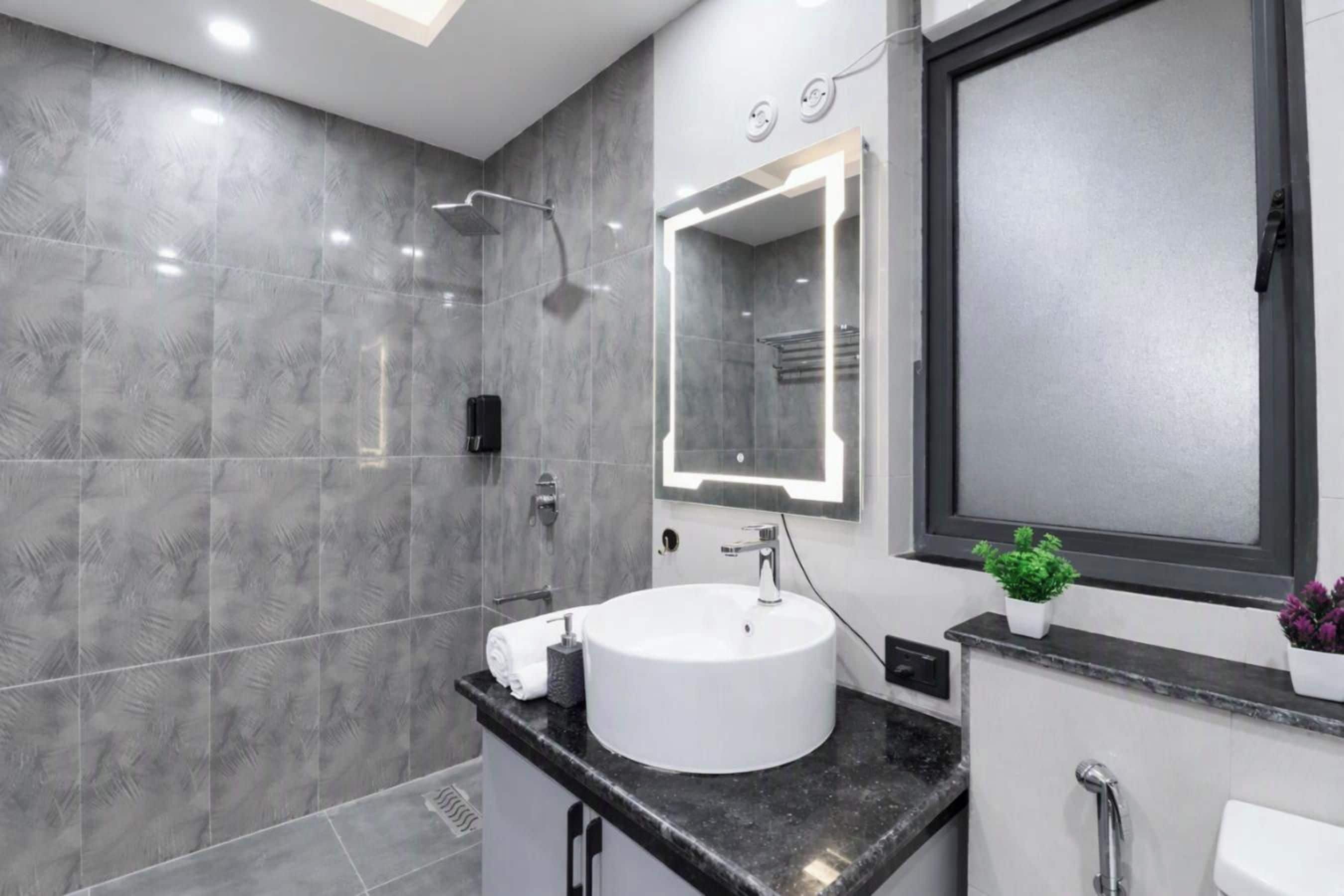 A modern bathroom with a large mirror, a white sink, and a shower.