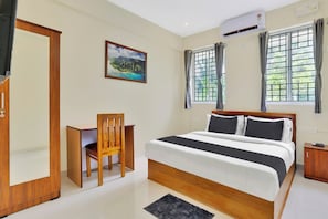 A hotel room with a bed, a desk, a chair, an air conditioning unit, and a window with curtains. - Super Collection O Lefort LUXE  (Trivandrum)