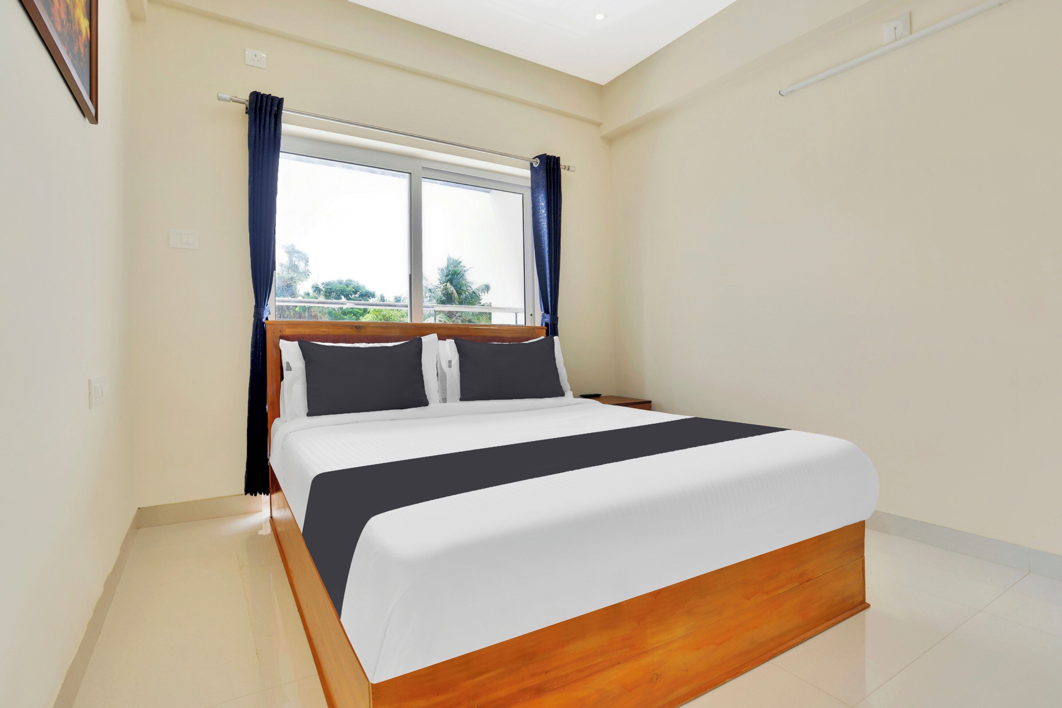 Habitación de hotel con una cama grande, una ventana con cortinas y vistas a zonas verdes.