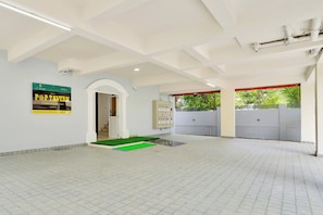 A spacious indoor area with a tiled floor, a green artificial grass entrance, and a sign advertising a home away from home experience. - Super Collection O Lefort LUXE  (Trivandrum)