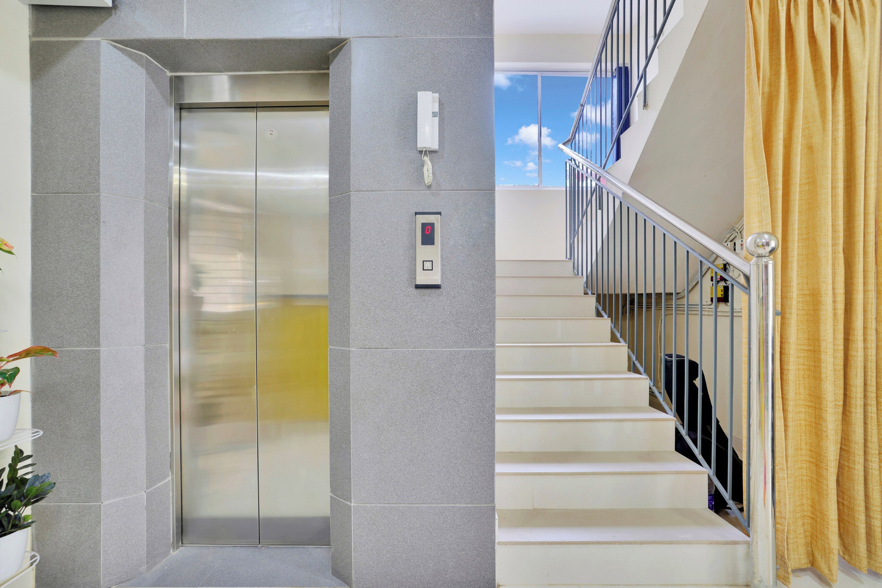 Ein Aufzug mit Bedienfeld und eine Treppe mit Geländer.
