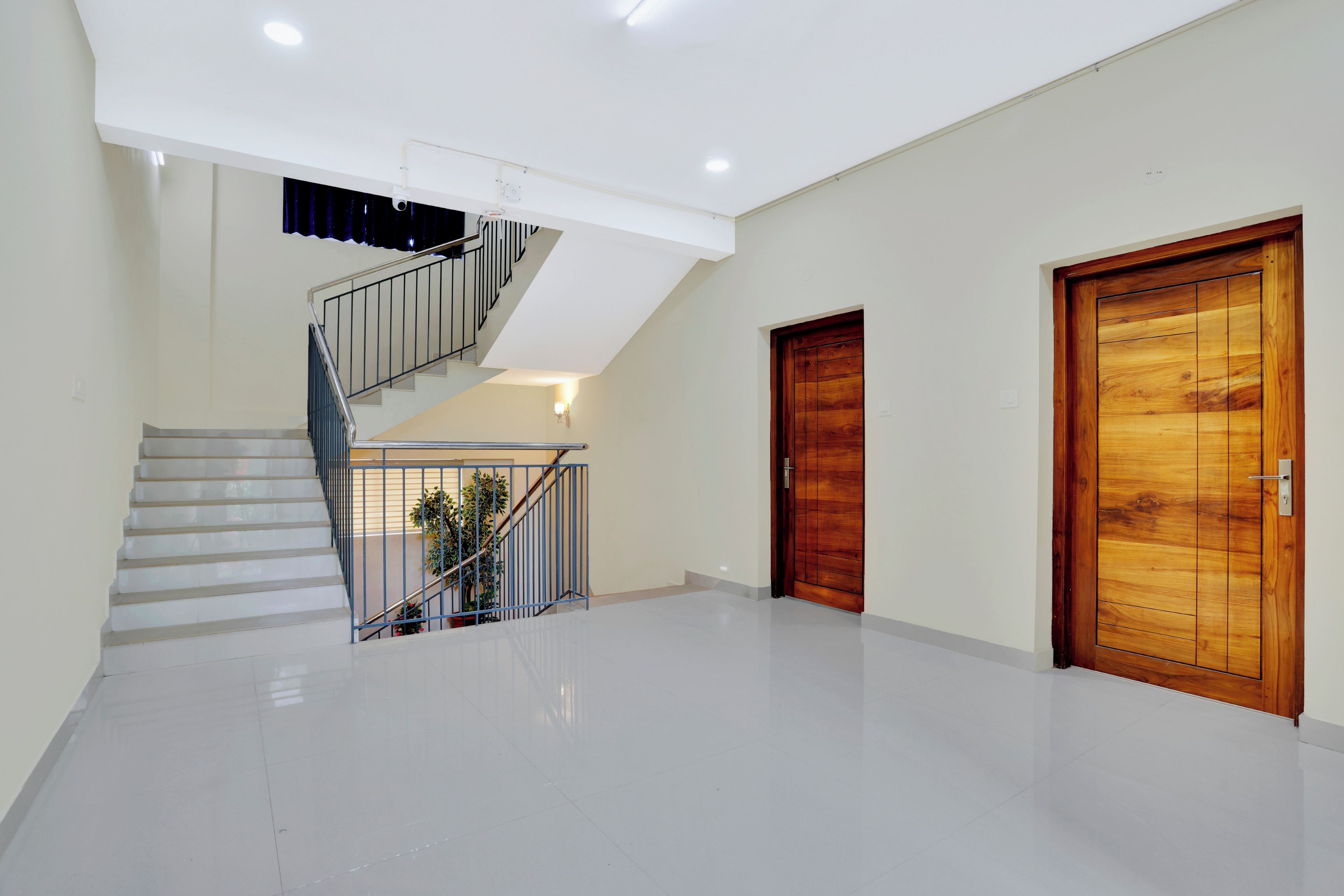 Un ambiente spazioso con una scala, una porta in legno e un muro bianco.