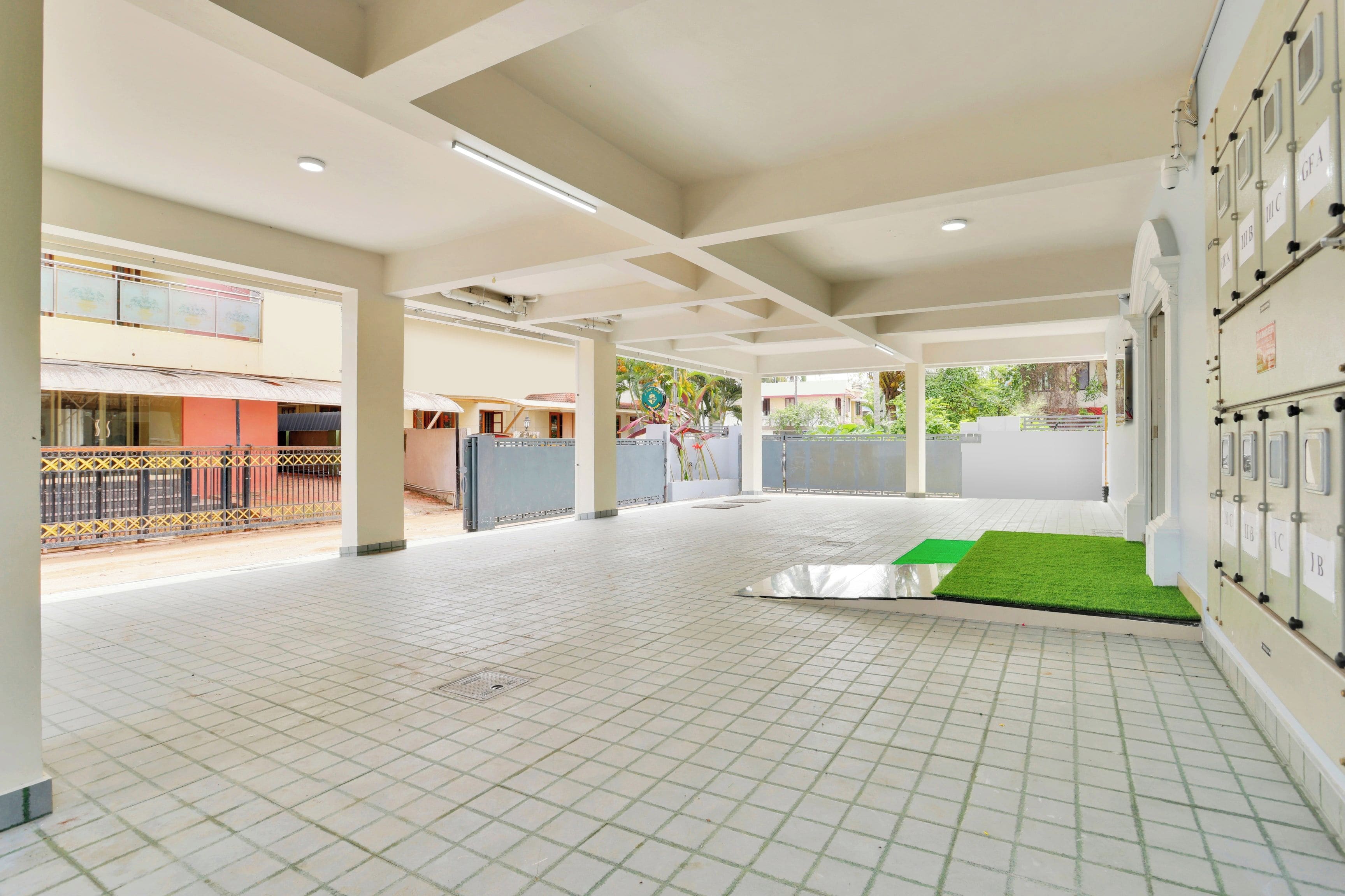 A spacious indoor area with tiled flooring, a green artificial turf section, and a row of lockers on the right.