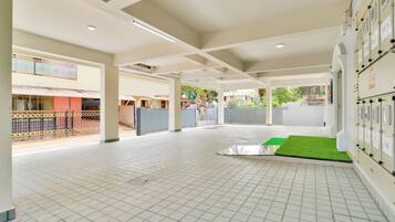 A spacious indoor area with tiled flooring, a green artificial turf section, and a row of lockers on the right.