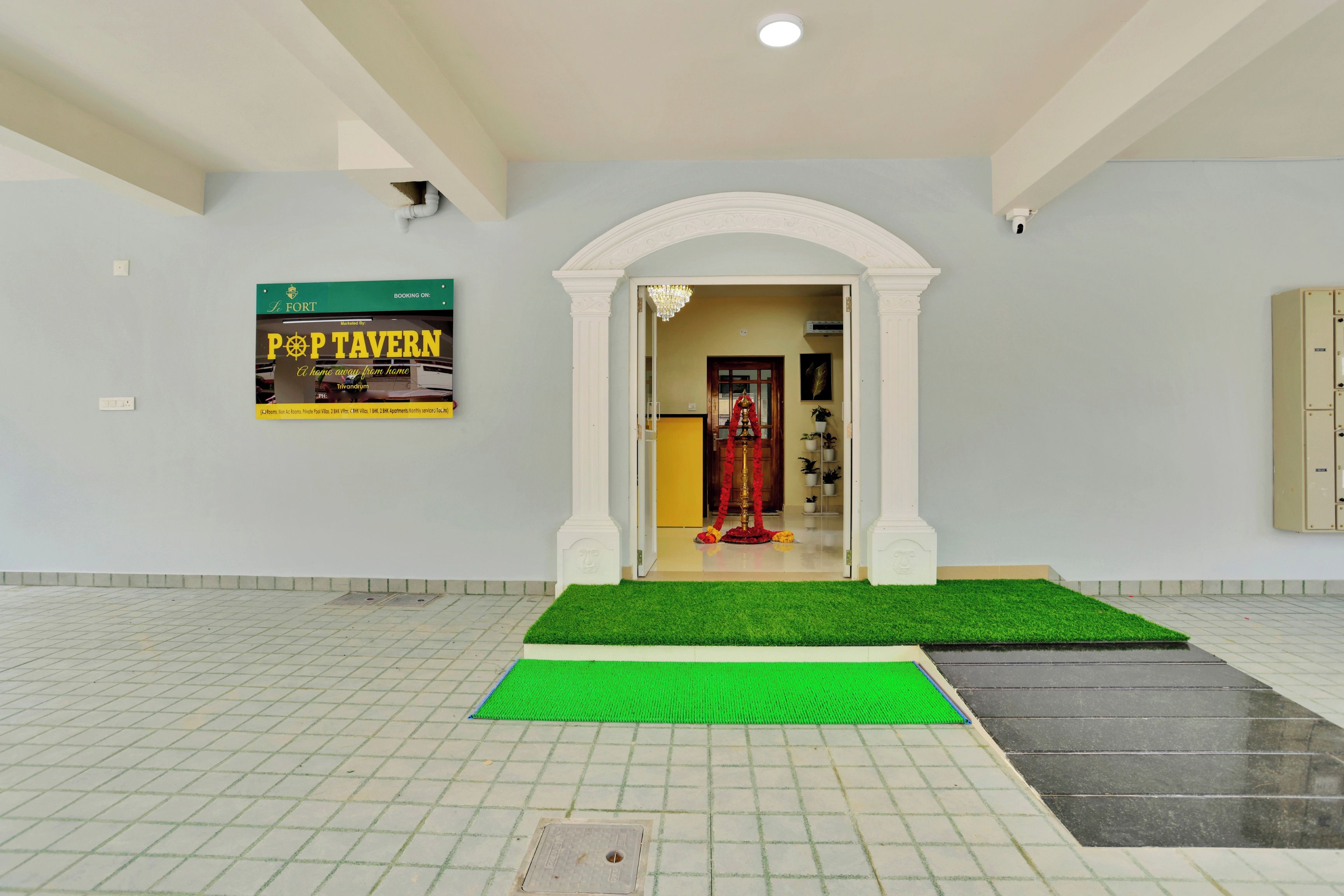 Una hall d'albergo con tappeto verde, un cartello per Pop Tavern e un arco decorativo.
