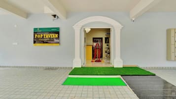 Una hall d'albergo con tappeto verde, un cartello per Pop Tavern e un arco decorativo.
