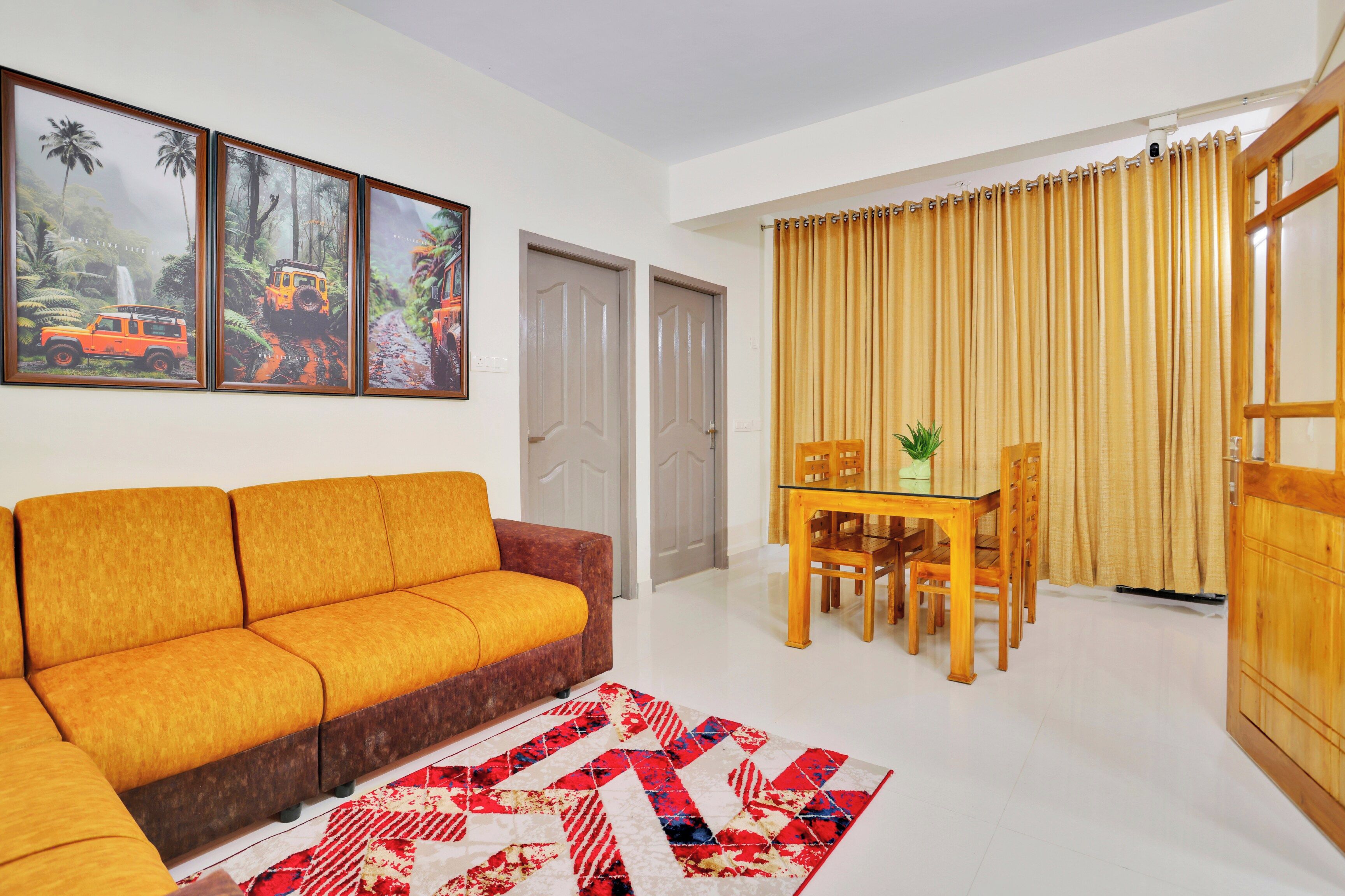 A living room with a sofa, a dining table with chairs, a rug, and a window with curtains.