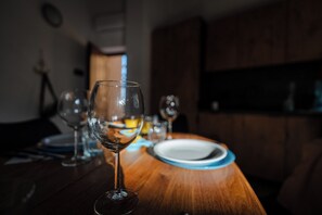 Ein Esstisch mit einem weinbecher im Fokus, einem Teller und verschwommenem Hintergrund, der einen Speiseraum andeutet.