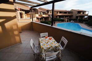 A balcony with a table and chairs, overlooking a swimming pool and a residential area. - La Perla Vermentino Costa Paradiso Sardinia (Costa Paradiso)