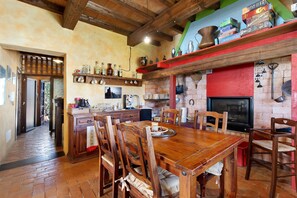 A rustic kitchen with wooden furniture, a dining table, and a red accent wall.