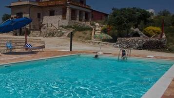 A swimming pool with a stone wall and a building in the background.
