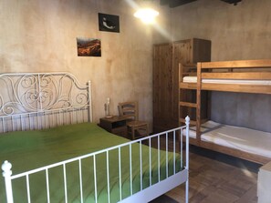 Een kamer met een stapelbed, een eenpersoonsbed, een houten garderobe, een stoel en een kleine tafel.