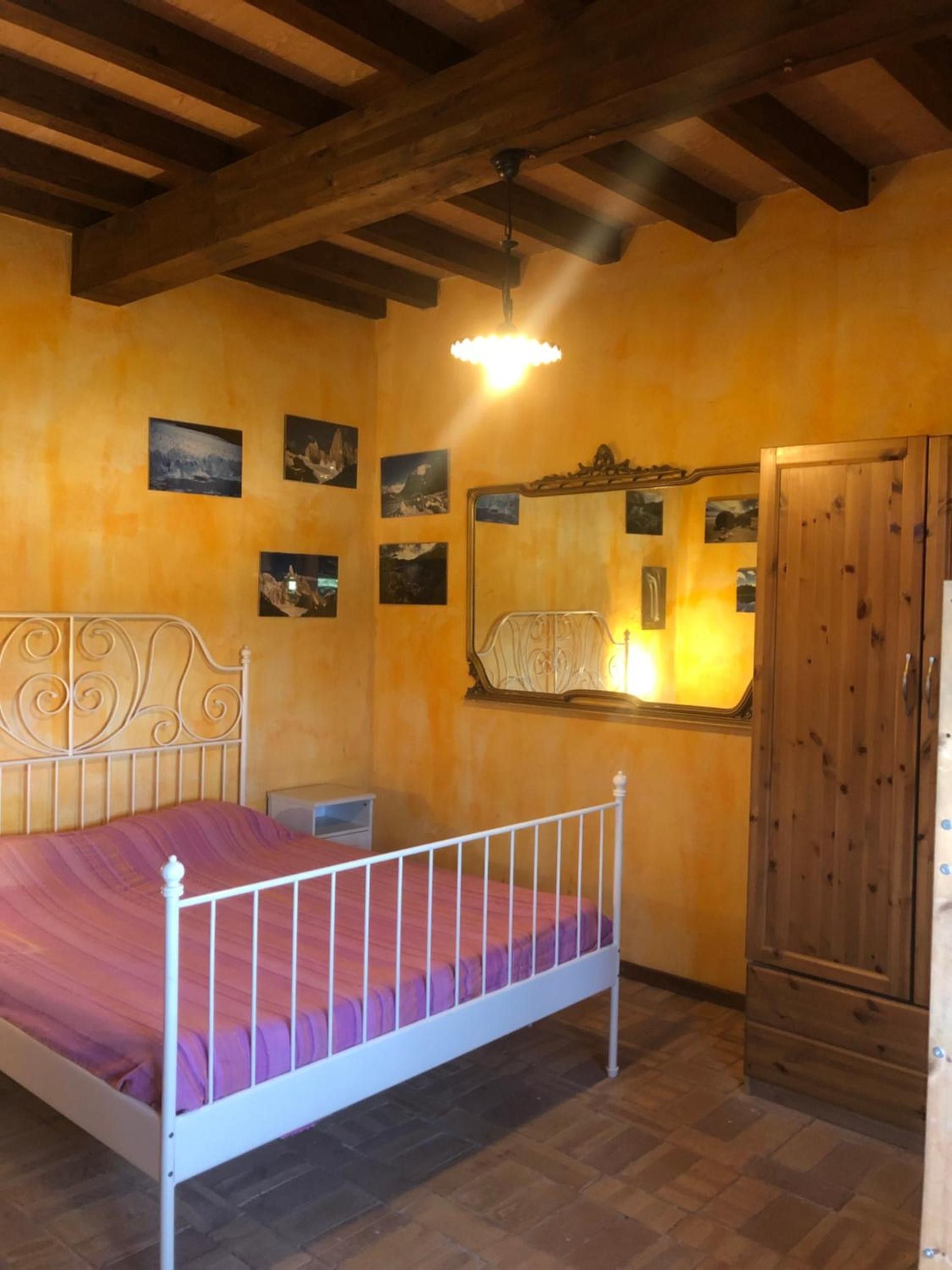 A bedroom with a bed, wooden wardrobe, and wall-mounted pictures.