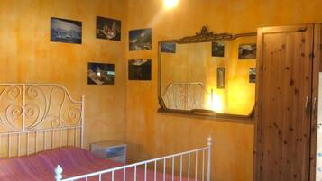 A bedroom with a bed, wooden wardrobe, and wall-mounted pictures.