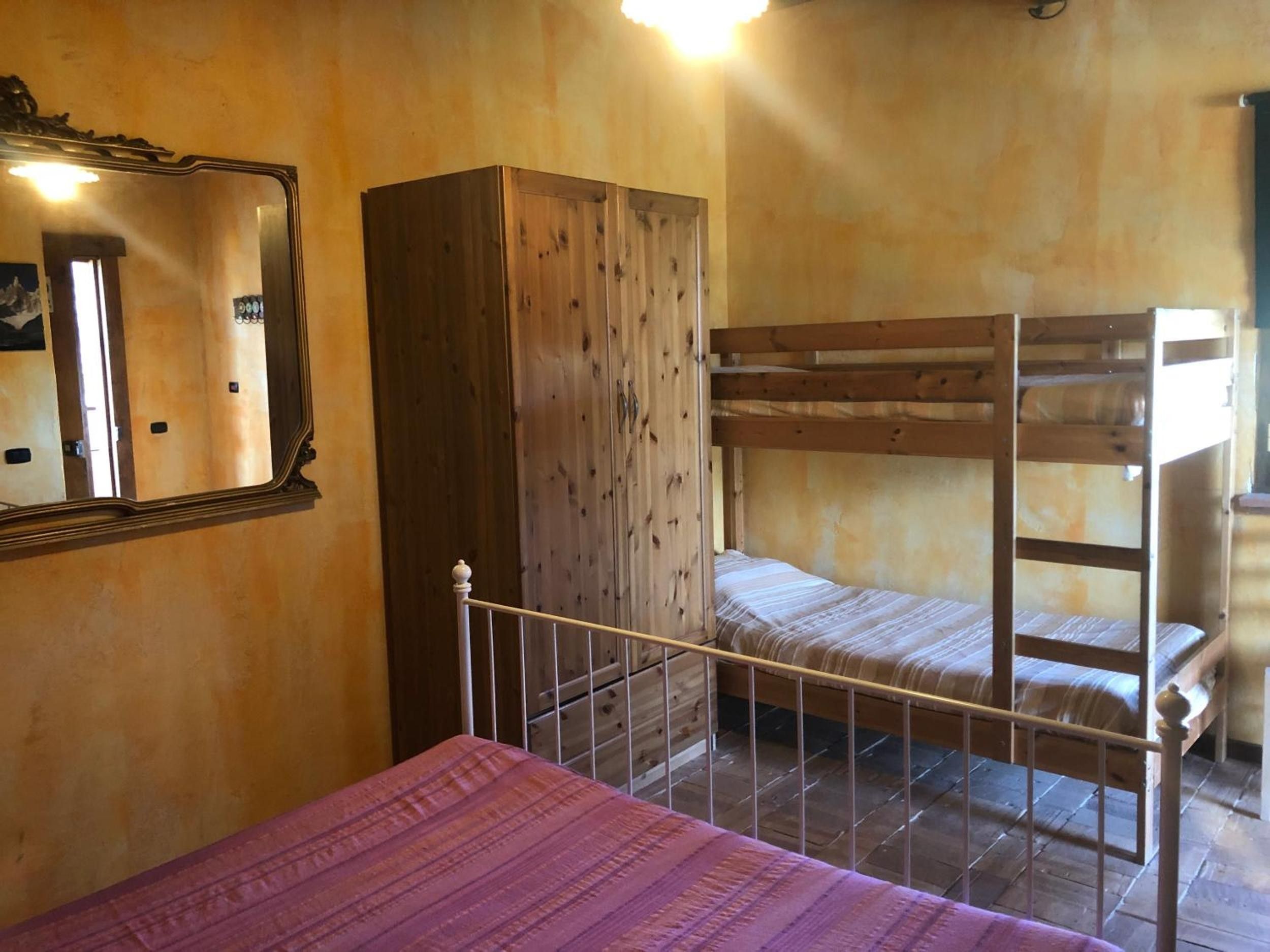 Ein Zimmer mit einem Etagenbett, einem Kleiderschrank und einem Spiegel an der Wand.