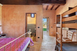 A narrow hallway with a bunk bed on the right, a single bed on the left, and a bathroom visible through an open door.
