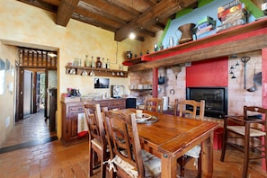 A rustic kitchen with wooden furniture, a dining table, and a red accent wall.