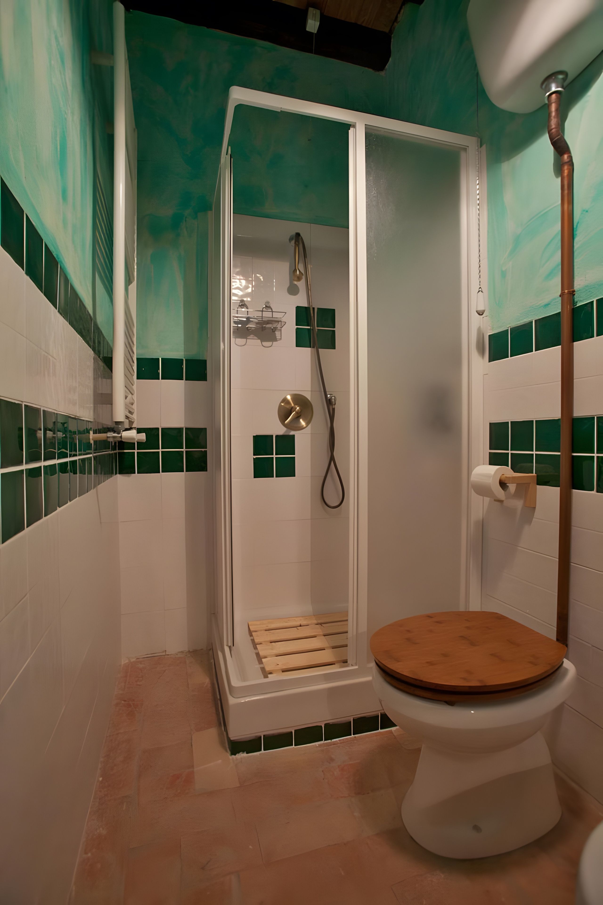 Un baño con cabina de ducha, inodoro y paredes con azulejos verdes.