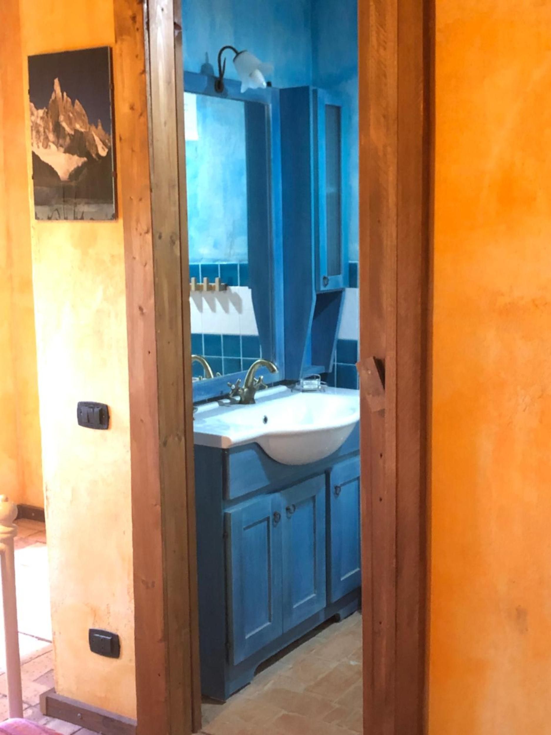 A bathroom with a sink, mirror, and blue cabinets.