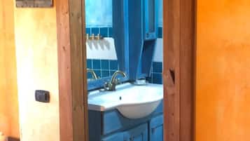 A bathroom with a sink, mirror, and blue cabinets.